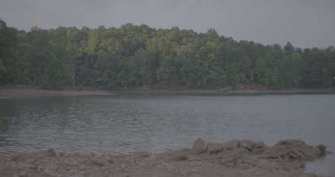 Calm lake with rocky shore in FG Stock Video