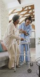 Vertical video of senior african american woman talking with female physiotherapist at home. senior healthcare and medical physiotherapy treatment.
