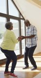 Vertical video of happy african american senior couple dancing. active retirement lifestyle and senior relationship.