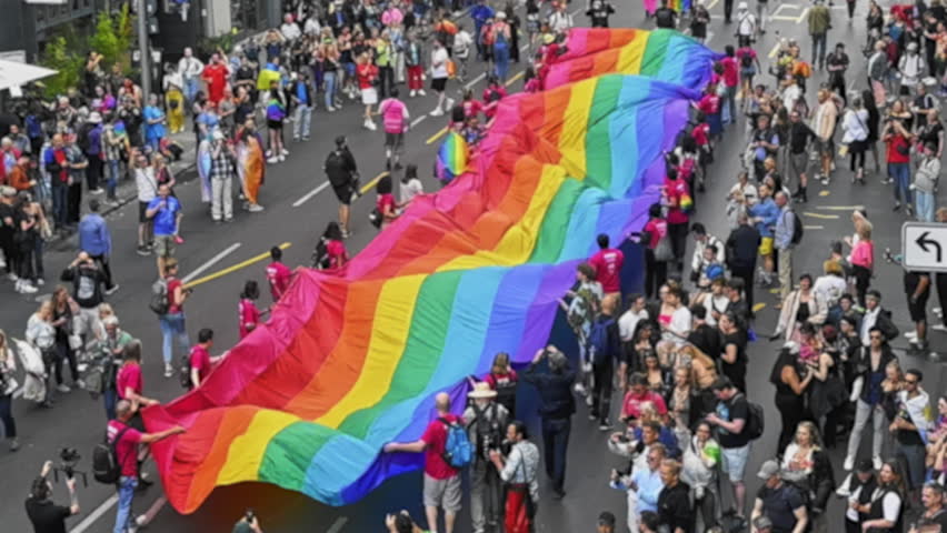 Many people wave huge rainbow flag. Big crowd walk city street. Fun lgbt community symbol. Stop no homophobia concept. Joy pride month fest. Bi gay men go csd love day party. Queer culture festival.