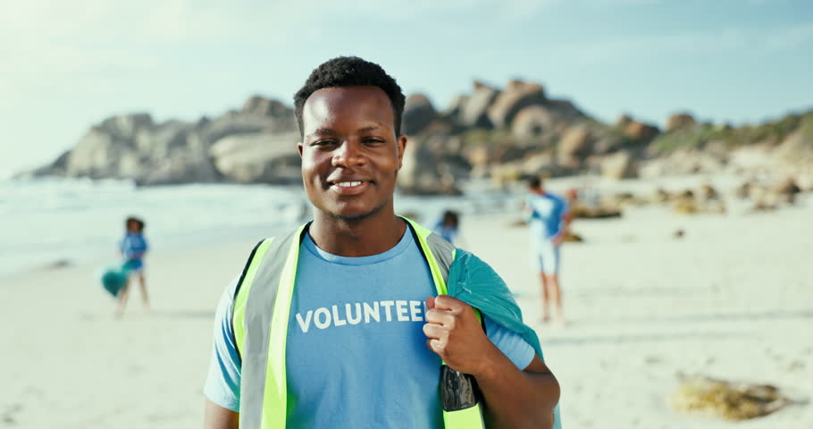 Portrait, volunteer and man at beach for cleaning trash, recycling and environment conservation. Face, charity and smile of African person at ocean for community service, ecology and bag for rubbish