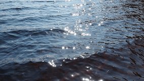 Ripples, sun glare, circles on waves. Sea ripples. Sun blurry glare on blue turquoise water. Reflection of light or spot of light. Relaxing slow motion video. Soft slow waves sunny path. Water bokeh