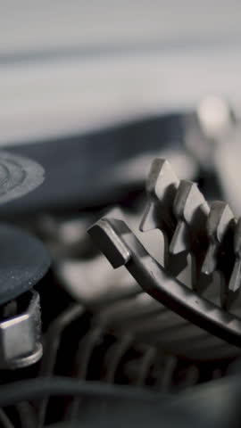 Close-up ribbon of an old vintage typewriter with metal bolts writing text in background - Slow Motion, vertcal