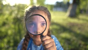 the girl holds magnifying glass in her hands. gaining knowledge and curiosity concept. a schoolgirl girl with a black magnifying glass is examining something, park on the background lifestyle - Powered by Shutterstock - Get 15% off with code: PIKWIZARD15