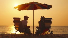 Happy couple on vacation at sea beach. Husband and wife resting, talking at sunny day on ocean shore water, sitting at sunbeds on beach. Family lovers relationships, vacation, travel resort concept. - Powered by Shutterstock - Get 15% off with code: PIKWIZARD15