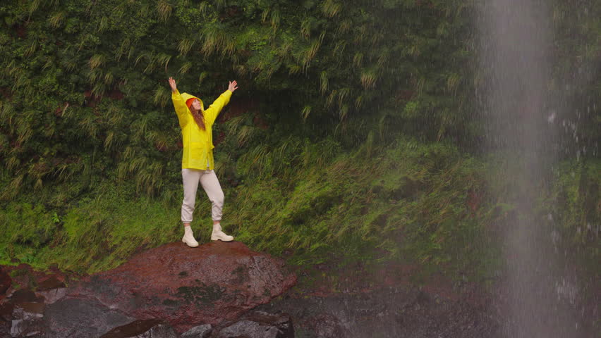 Woman open arms under waterfall, hiking in nature adventure to explore on outdoor holiday vacation. Travel, freedom or journey