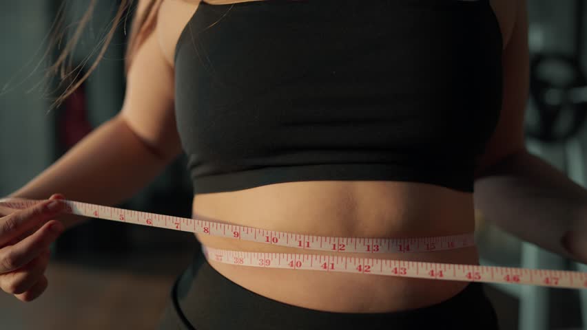Young woman trying lose weight. Unrecognizable girl woman shows weight loss big size, sports gym body slimming in studio. Waist dieting healthy lifestyle. The concept of weight loss and calorie diet. Royalty-Free Stock Footage #3454623597