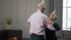 Senior happy couple dancing at home. Sincere loving old wife husband in festive hats attires enjoy romantic dance celebrating husband's birthday holidays. Celebrate, lifelong marriage concept. - Powered by Shutterstock - Get 15% off with code: PIKWIZARD15