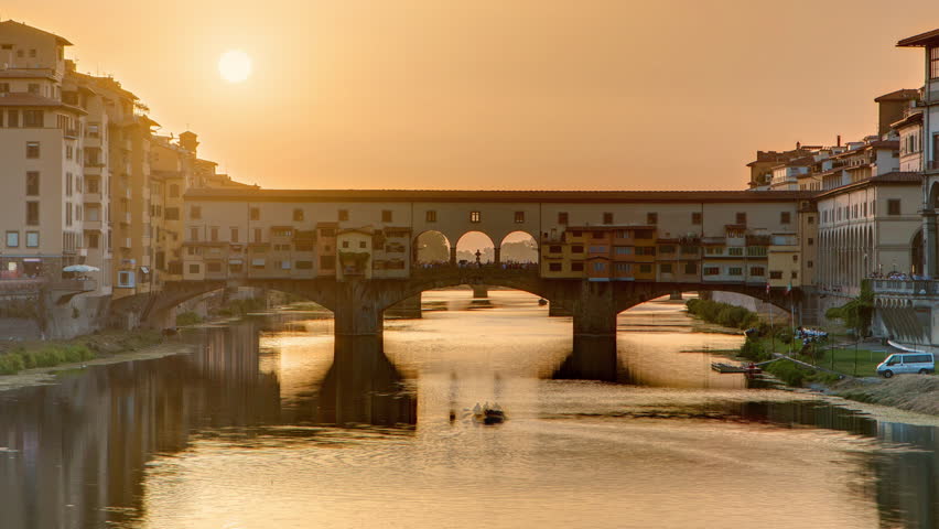 Sunset view of Florence Ponte Vecchio over Arno River in Florence timelapse, Italy. Florence architecture. One of the main landmarks in Florence with orange sky above