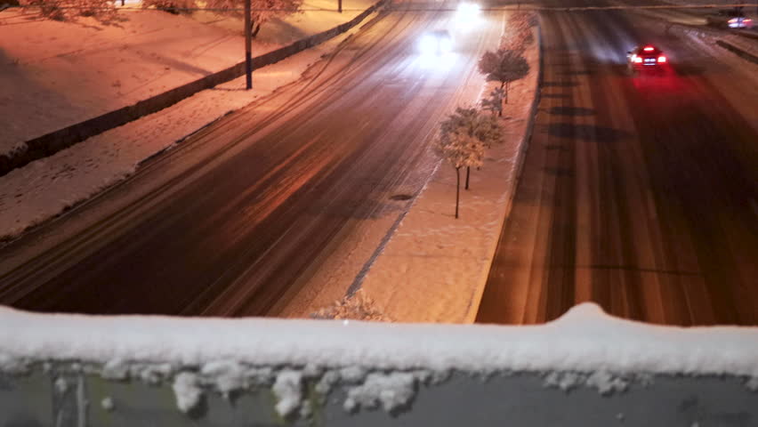 Winter city traffic on snowy evening, multi lane roads partly covered with snow and illuminated by street lights, snow-covered trees and sidewalks, high angle view, uhd, 4k, 3840, 2160 Royalty-Free Stock Footage #3454682841
