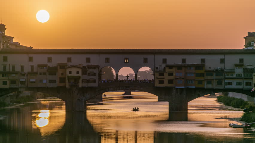 Sunset view of Florence Ponte Vecchio over Arno River in Florence timelapse, Italy. Florence architecture. One of the main landmarks in Florence. Close up view with orange sky