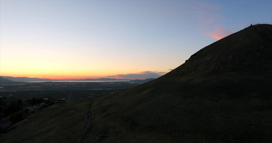 Drone rising on hill with Salt Lake City industrial area in background at sunset, Utah in USA. Aerial ascending and sky for copy space