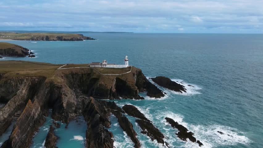 drone flying over a white lighthouse and rocks, ocean view, Ireland