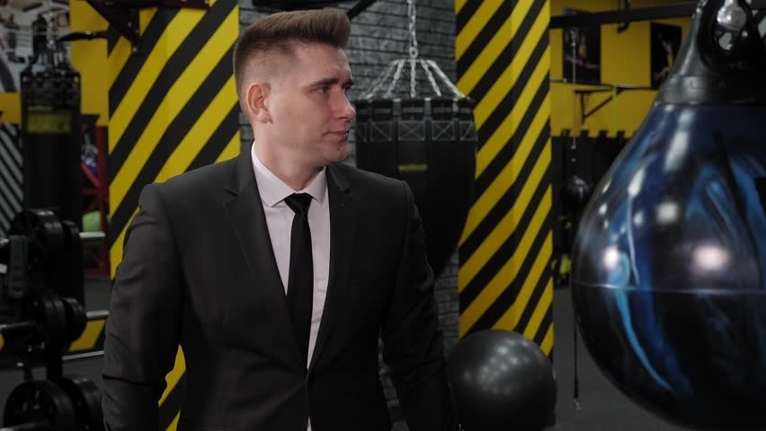 Close-up of a successful serious businessman in boxing gloves, boxing in the ring after a long working day. 
