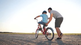 family play in the park. father teaching son to ride a bike. happy family kid dream concept. son learn to ride bike silhouette. father supporting child son riding bike summer in the park sunset - Powered by Shutterstock - Get 15% off with code: PIKWIZARD15