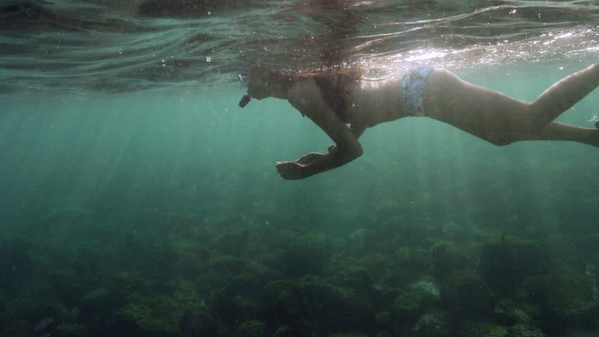 Beautiful girl in bikini snorkeling and enjoying her vacation.