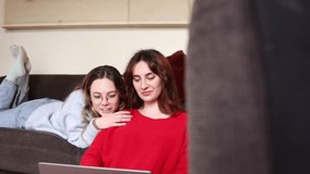 Female gay couple lie on the sofa conducting research on a laptop in their living room. Two lesbian women recline on the sofa, engaged in researching on a laptop in their living room. - Powered by Shutterstock - Get 15% off with code: PIKWIZARD15