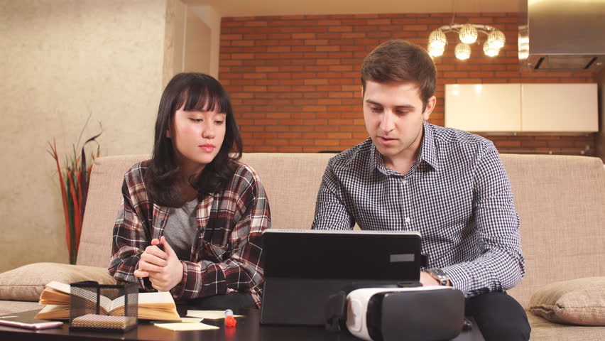 Young business couple using laptop at home.