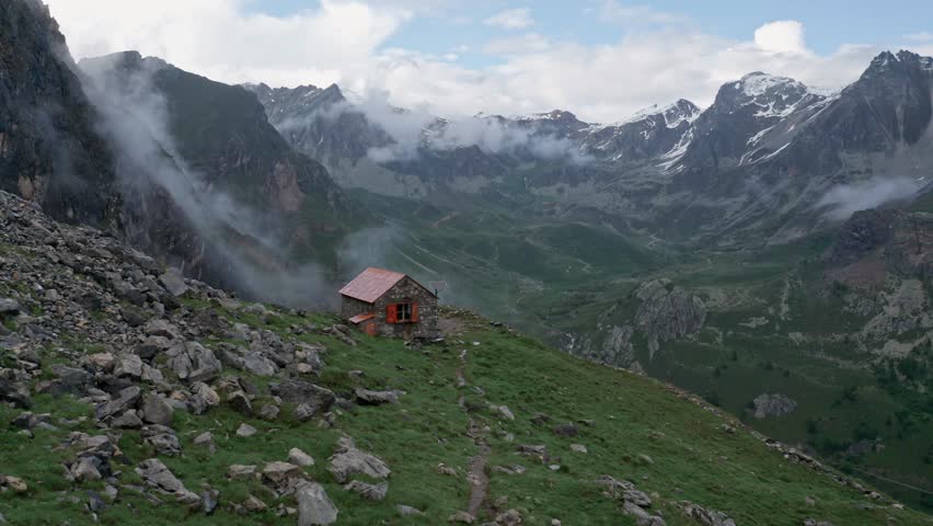 Lone mountain refuge amid foggy alpine peaks, a serene escape in nature, daylight, wide shot