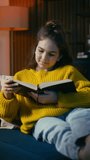 Teenage girl reading a Bible while resting on sofa, religious literature