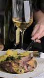 baked duck in a serving plate with a side dish and a glass of wine. Women's hands cut a duck. Vertical video. High quality footage