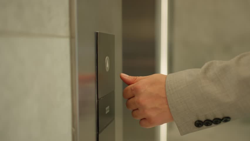 The Decisive Moment of Corporate Access. A close-up of a businessman's hand pressing an elevator button, symbolizing decision and movement.