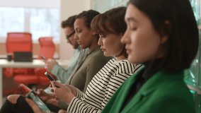 Carefree casual young people sitting in lobby of civil service building browsing web pages in Internet on smartphone while waiting to meet with representative. Shooting in slow motion. - Powered by Shutterstock - Get 15% off with code: PIKWIZARD15