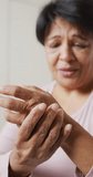 Vertical video of senior biracial woman touching her hand. healthy and active retirement at home.