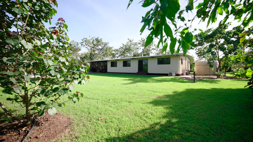 Rural Large Property Small Rectangular House With Large Backyard on Sunny Day, Dolly Reveal Past Foliage. Exterior of home for real estate property.