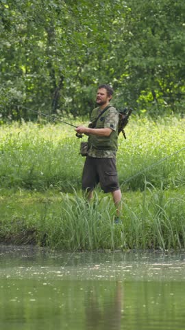 Three anglers enjoying fishing surrounded by the lush green nature of the river shore, wide shot. Outdoor hobby and activity concept. Vertical video