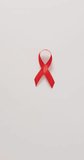 Vertical video of red ribbon on beige background. health, prevention, medicine, symbols and cancer awareness concept.