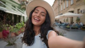 Young happy smiling tourist Indian Arabian lady woman female student waving hand social media vlogger holding smartphone talking camera shooting making online video call virtual mobile outside street - Powered by Shutterstock - Get 15% off with code: PIKWIZARD15