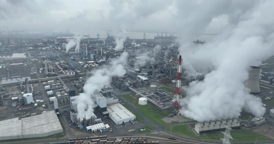 Aerial birds eye view on the chemical industry at the port of Antwerp, Belgium. Smoking fumes and heavy industry in operation.