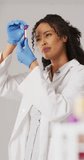Vertical video of happy biracial female lab worker with sample. science, medicine and working in laboratory concept.