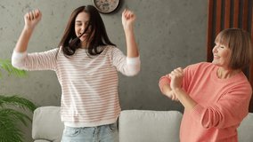 Two adult women older mature mom young kid wears casual clothes dance sing near gray sofa couch stay home flat rest relax spend free spare time in living room indoor. Mother's Day love family concept - Powered by Shutterstock - Get 15% off with code: PIKWIZARD15