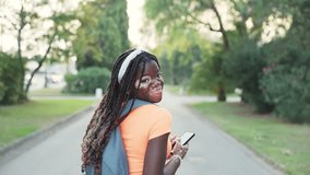 Portrait of a young student girl with vitiligo smiling at the camera as she walks around the campus. Slow motion video of a young female student with a backpack smiling