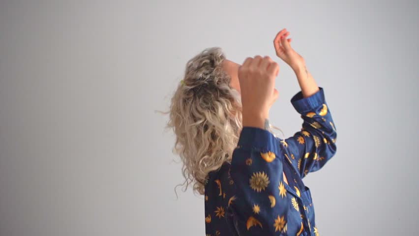 Young blonde woman with curlers having fun dancing in a starry dress while preparing to go out Royalty-Free Stock Footage #3455009787