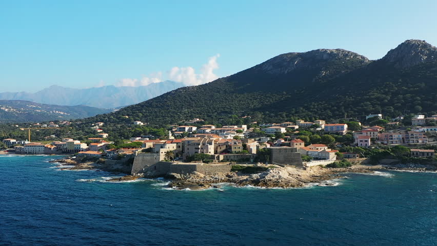 The city of Calvi and its medieval castle at the foot of the mountains, in Europe, in France, in Corsica, by the Mediterranean Sea, in summer, on a sunny day.
