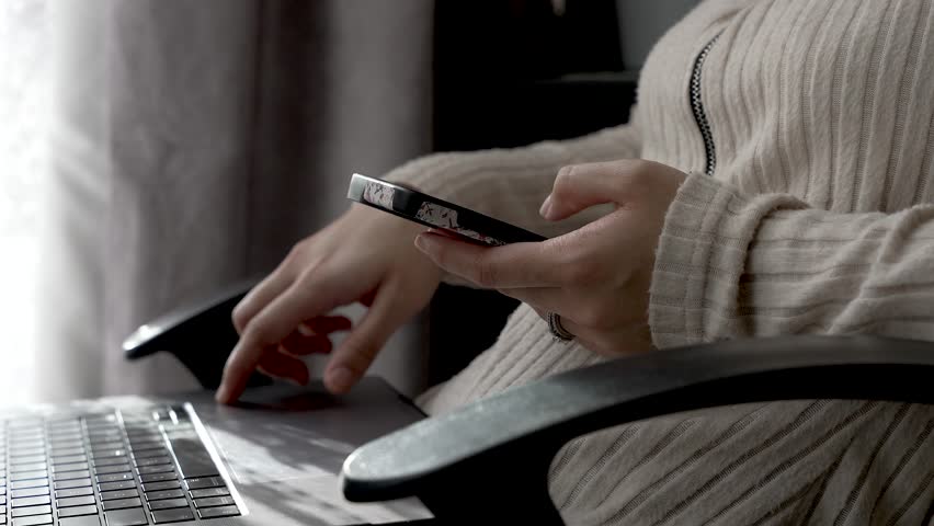 Close Up Of Female Hand, Scrolling On Mobile With Laptop On Lap. Static Shot