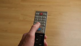 remote control. A man presses a broken button. Can't change TV channel.