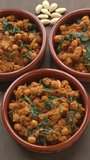 Homemade Spinach and Chickpeas (Espinacas con Garbanzos). Main seasonings (cumin seeds, smoked paprika, and roasted almonds) on the table. Table spin. Vertical video.