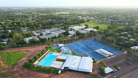 Aerial drone of Recreational Swimming Pool and Tennis Courts With Golden Hour Glow on Horizon Sky, Pull Away Moulden Northern Territory Australia - Powered by Shutterstock - Get 15% off with code: PIKWIZARD15