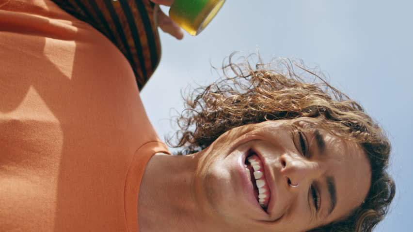 Cheerful skateboarder relaxing street hold longboard sunny day vertical close up. Portrait trendy curly skater smiling feeling happy enjoying extreme hobby. Carefree joyful guy posing with skateboard