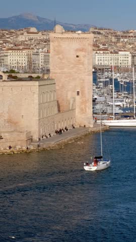 Yachts coming to Marseille Old Port (Vieux-Port de Marseille) on sunset and Fort Saint-Jean. Marseille, France. Camera pan