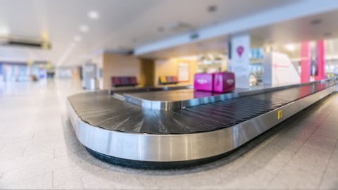 Time-lapse of modern airport luggage conveyor belt. People come from airplane, waiting and picking their bags and cases and leave. Tilt-Shift effect.