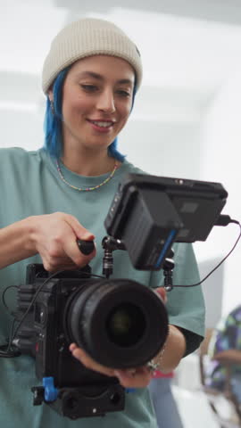 Vertical Screen: Slow Motion Shot of Female Cinematographer Working On a Filming Set, Using Digital Camera to Shoot High-Quality Footage for Cinematic Project. Creative Woman Operating a Camera