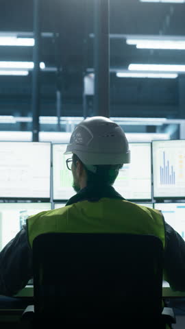 Vertical Screen: Backview To Close Up Of Caucasian Male Engineer Using Multi Monitor Workstation To Control Production on Assembly Line With Robotic Arms. Man Adjusting Manufacturing Processes Royalty-Free Stock Footage #3455191377