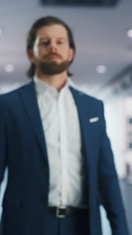Vertical Screen: Portrait of a Confident Young Caucasian Businessman Standing in Office in a Blue Business Suit. Successful Corporate Manager Posing for Camera with Crossed Arms, Smiling Cheerfully