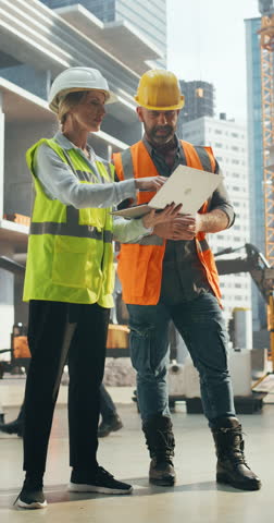 Vertical Screen: Female Civil Engineer and a Construction Manager Having a Meeting to Discuss Project Plans of a Real Estate Building. Specialist Using Laptop Computer to Oversee the Project Royalty-Free Stock Footage #3455206733