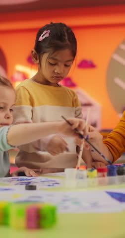Vertical Screen: Adorable Multiethnic Girls Using Watercolor to Create Colorful Paintings on Paper. Cheerful Female Teacher Spending Productive Time in Preschool, Teaching Kids to Paint in Art Class Royalty-Free Stock Footage #3455208651